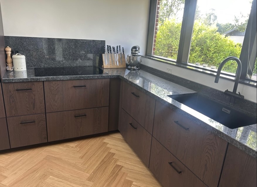 Steel Grey granit — Klassisk mörk granit i matt mot valnötsluckor