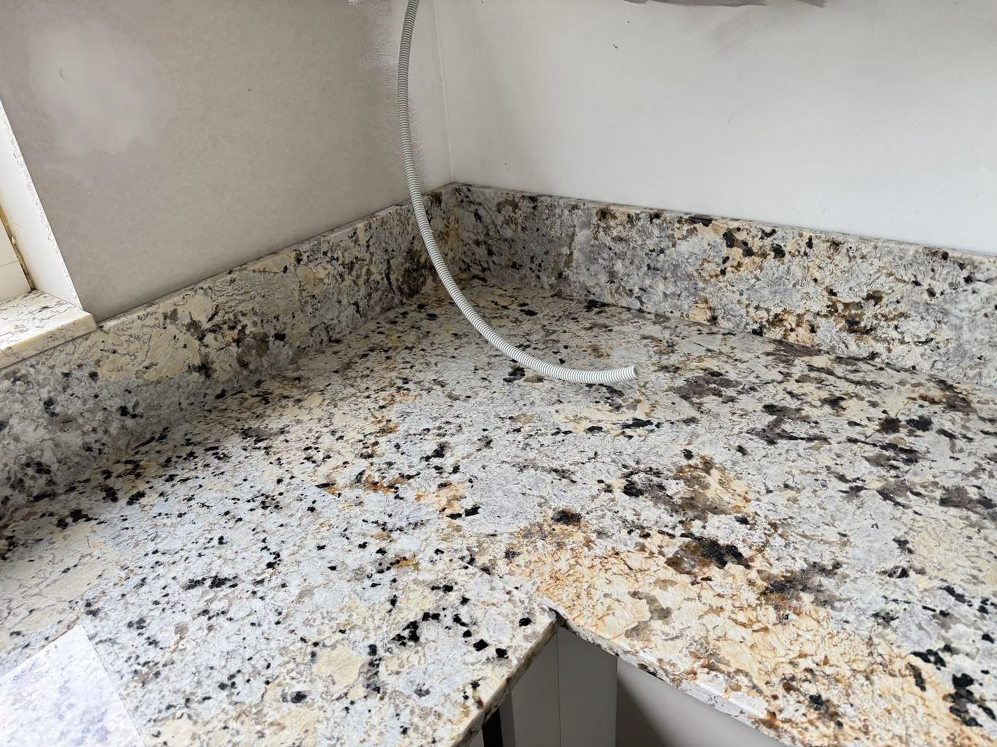 Hörn av köksbänkskiva i polerad Alaskan white granit med uppvikt stänkkant i Kristianstad.