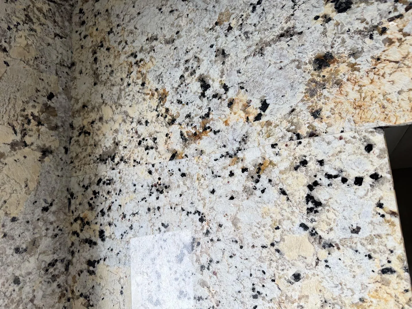 Närbild på ådring och skarv i polerad Alaskan white granit på installerad köksbänkskiva i Kristianstad.