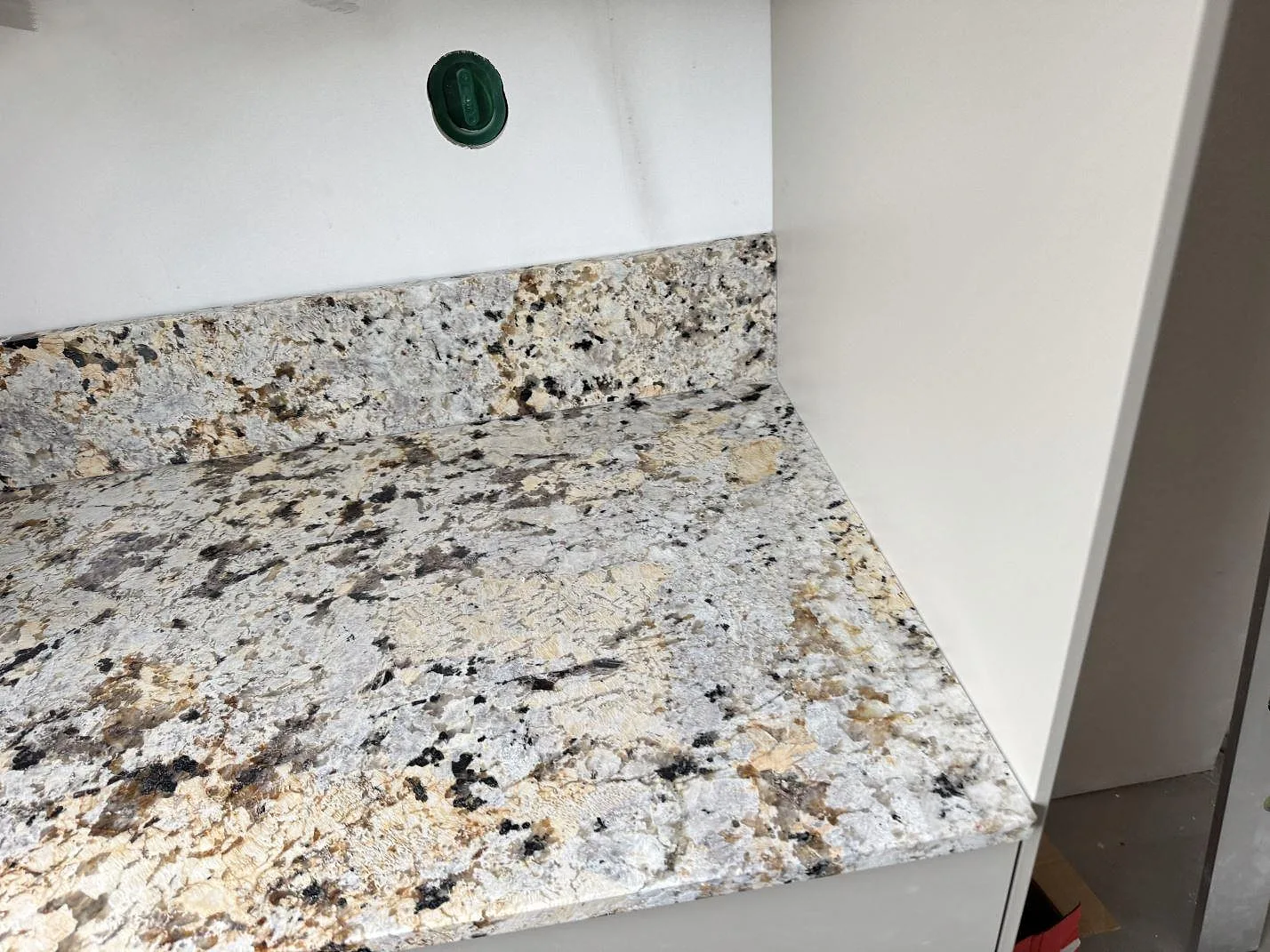 Sidoyta i polerad Alaskan white granit med stänkkant mot vägg i ett kök i Kristianstad.