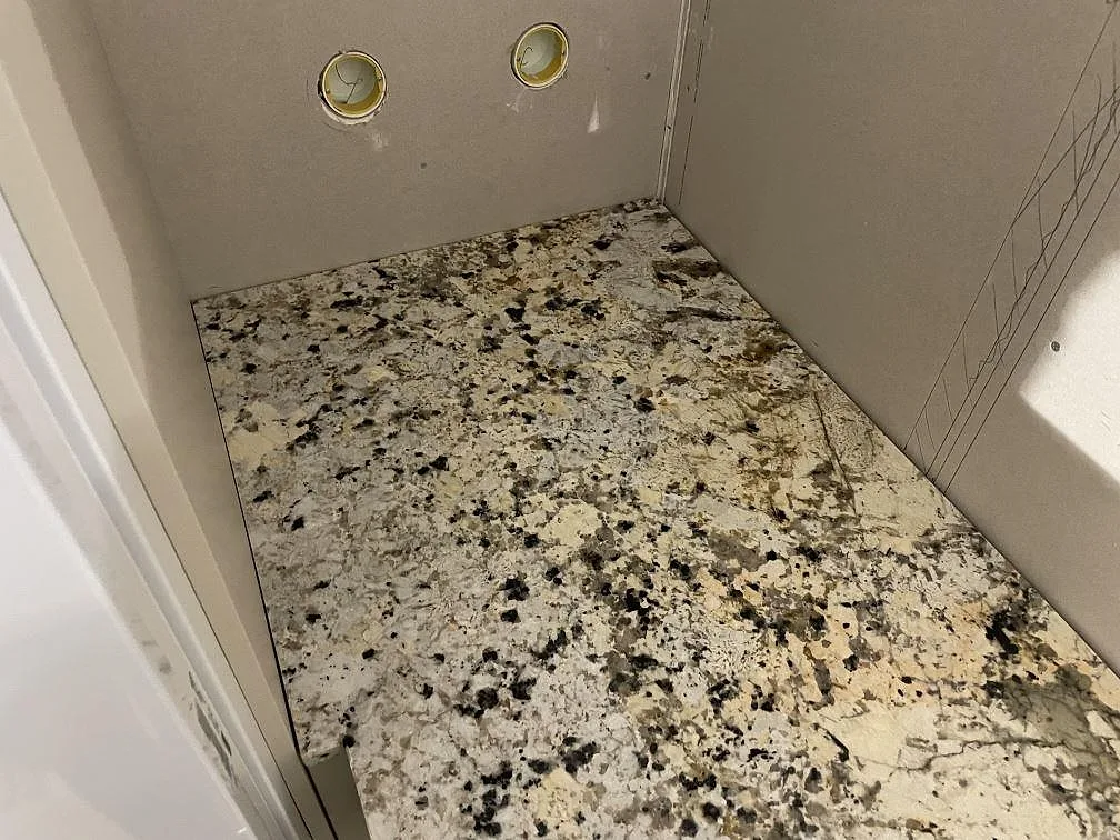 Närbild av polerad Alaskan white granit på en kort bänkskiva vid vägg i ett kök i Svartsjö.