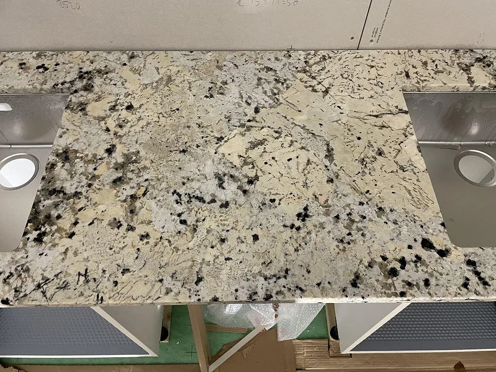 Närbild av polerad Alaskan white granit mellan två rostfria diskhoar i ett kök i Svartsjö.