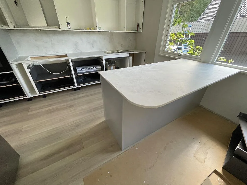 Köksbänkskiva i matt Ambiente Light Terra Surface keramik med köksö, rundat hörn och heltäckande stänkvägg i ett kök i Järfälla.