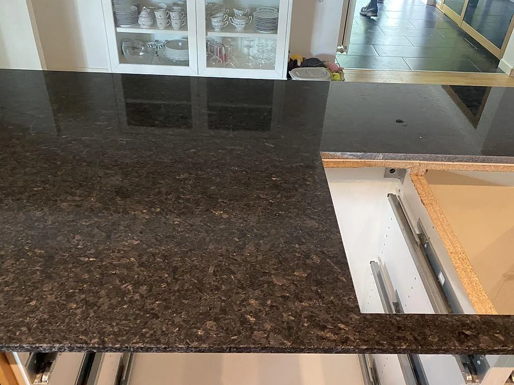 Polerad Angola Black granit med hällöppning och öppna köksstommar under montering i Eslöv.