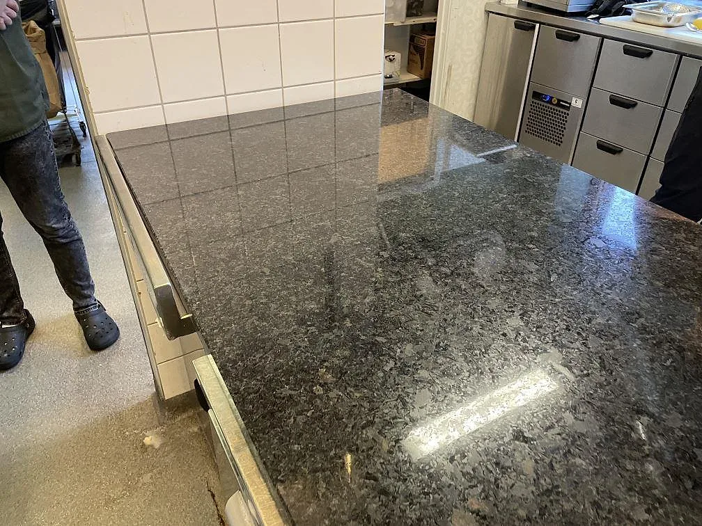 Närbild av polerad Angola Black granitbänkskiva med specklad svart yta i Genarp.