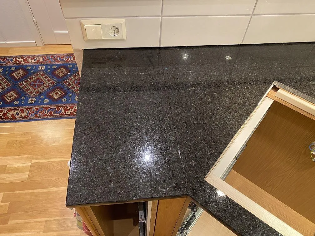 Närbild av polerad Angola Black granit i hörnet av köksbänken med öppning i stomme och blank yta i Hässleholm.