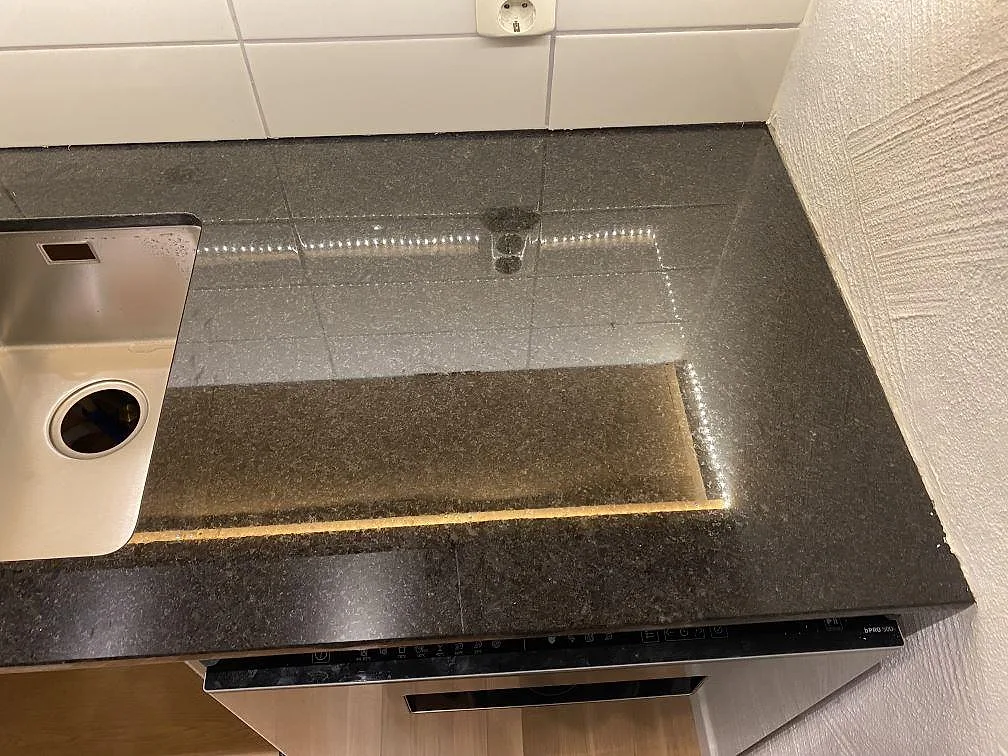 Polerad Angola Black granit vid häll och rostfri diskho, med tät svart stenyta i ett kök i Hässleholm.