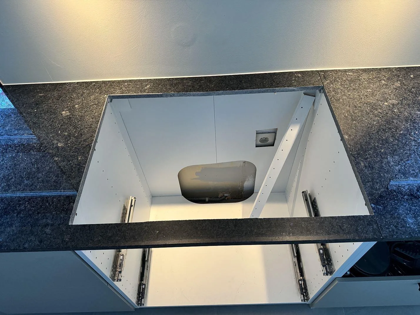 Installationsdetalj av polerad Angola Black granit runt öppna köksstommar, mörk blank bänkskiva under montering i HJÄRUP.
