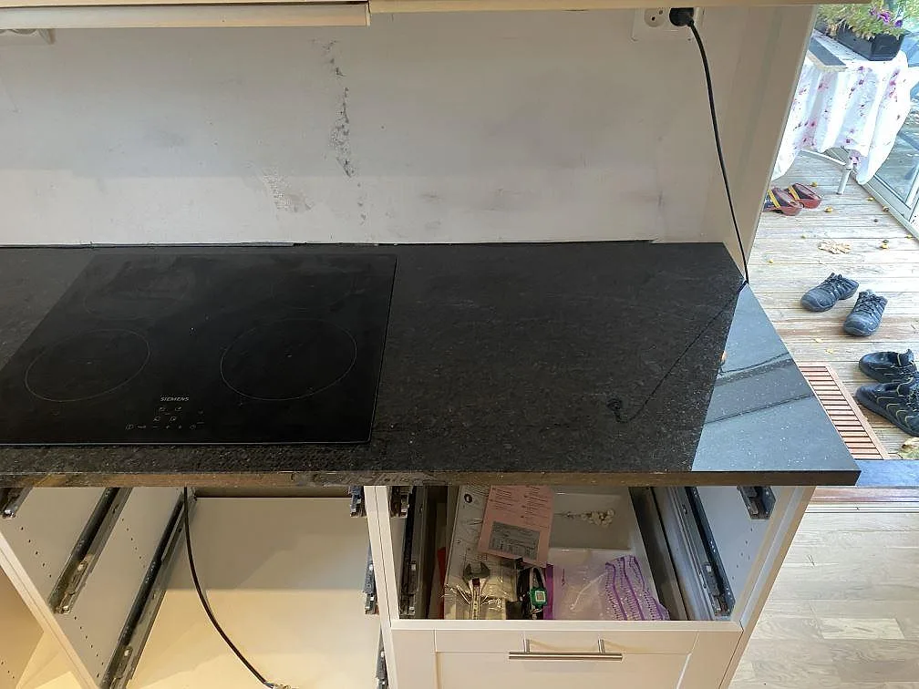 Detalj av polerad köksbänkskiva i Angola Black granit vid en svart häll och mörk stenyta i Höllviken.