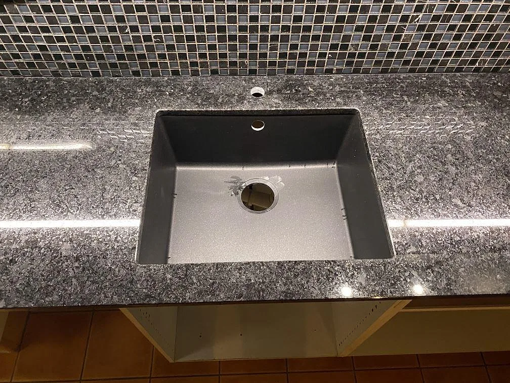 Närbild på polerad Angola Black granit med synlig diskho i köksbänkskiva i Höllviken.