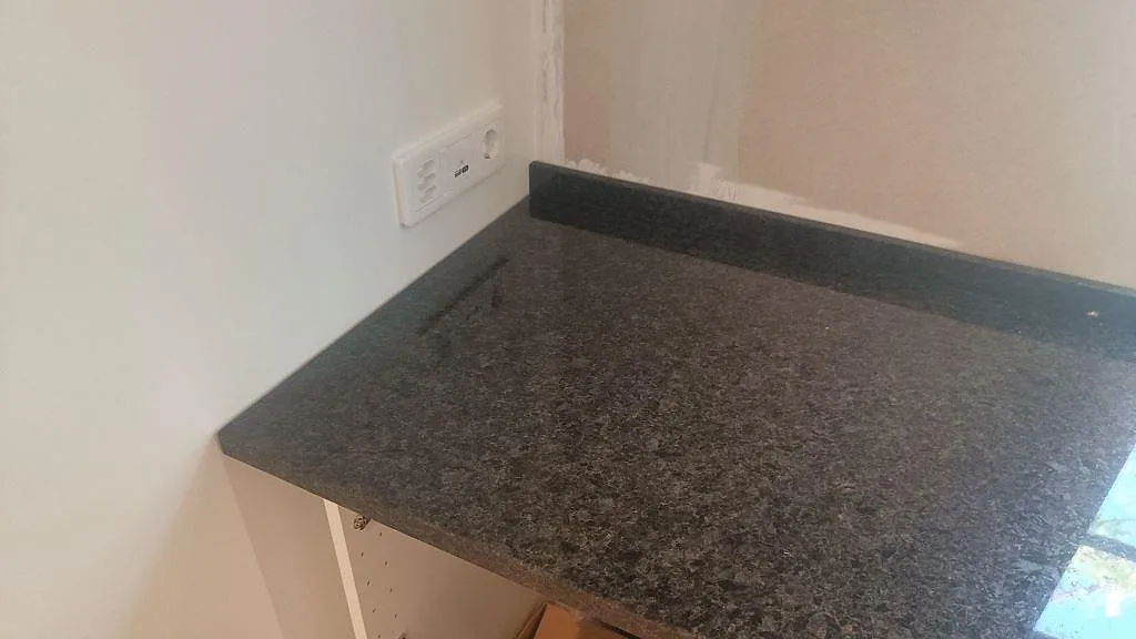 Sidoyta av polerad Angola Black granit med låg stänkkant och öppen köksstomme i Lund.