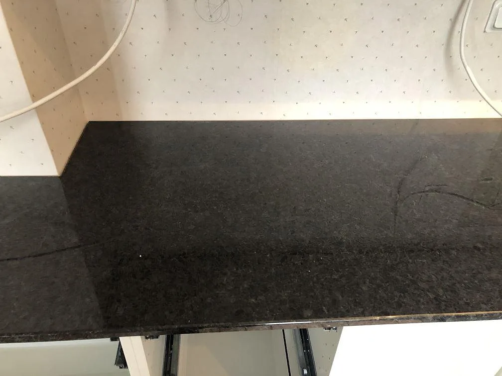 Köksbänkskiva i polerad svart Angola Black-granit med synliga ljusa kristallstänk i ett kök i Malmö under montering.