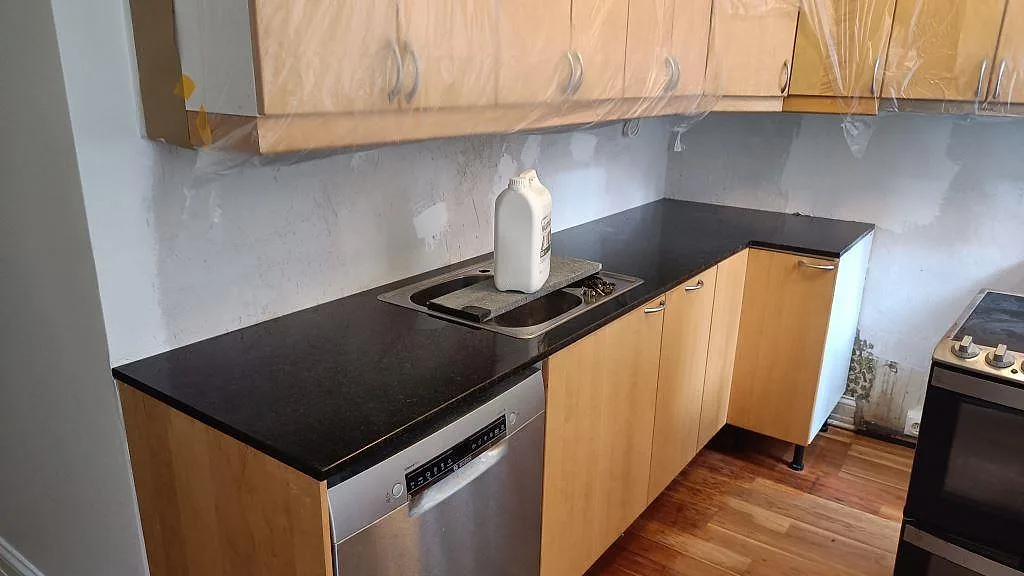 Köksbänkskiva i polerad Angola Black granit, 20 mm, monterad i ett L-format kök under renovering i Malmö.