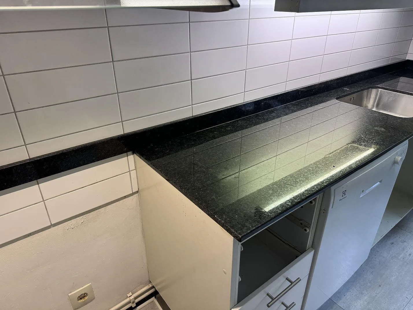 Polerad Angola Black granit som köksbänkskiva längs kaklad vägg med svart stenkant i Malmö.