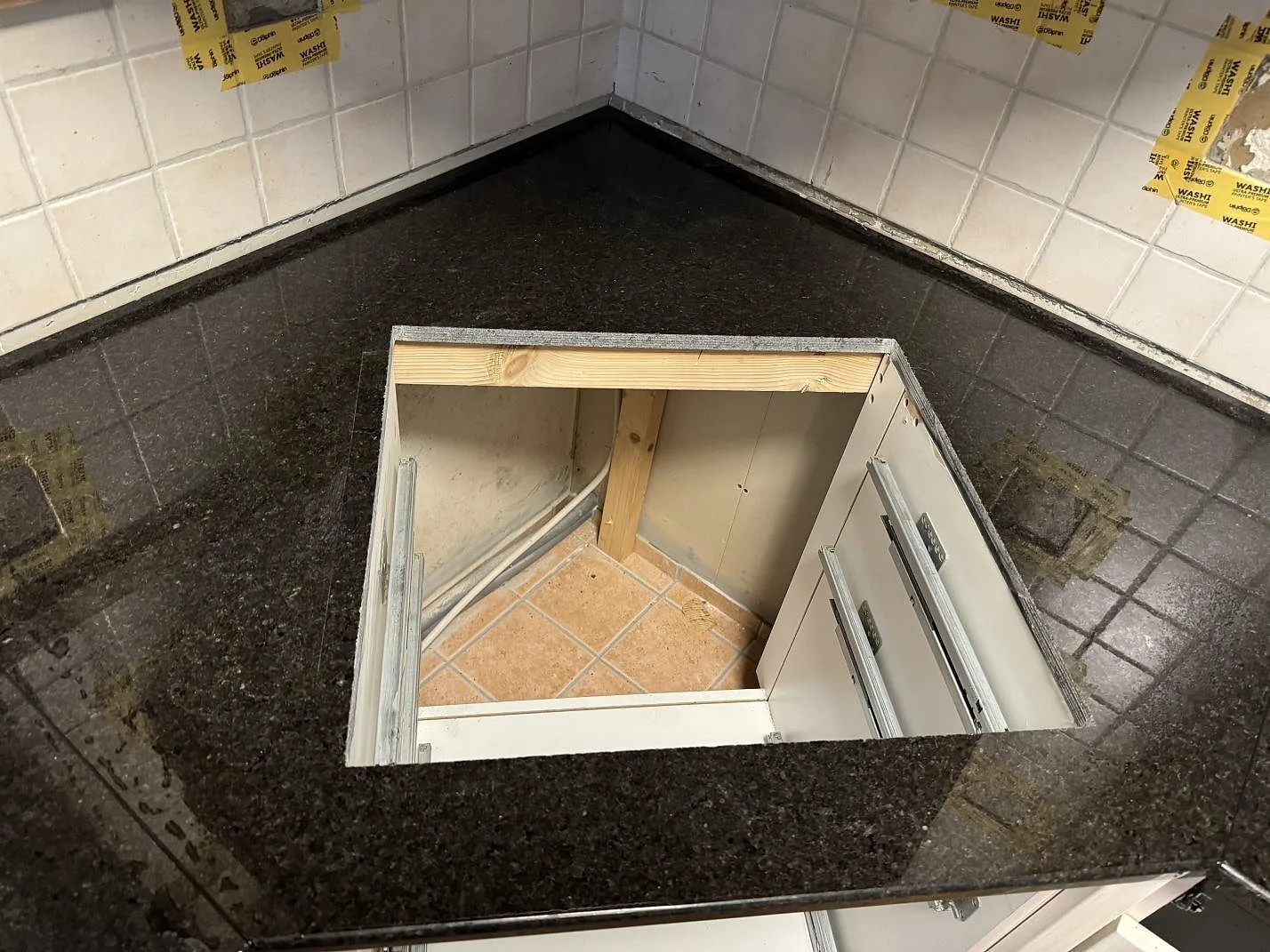Köksbänkskiva i mörk Angola Black granit, polerad, runt ett större rektangulärt urtag i hörnet av köket i Malmö.