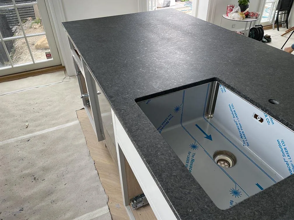 Detalj av matt Angola Black granit på köksö med underlimmad rostfri diskho och mörk stenyta i Rungsted Kyst.
