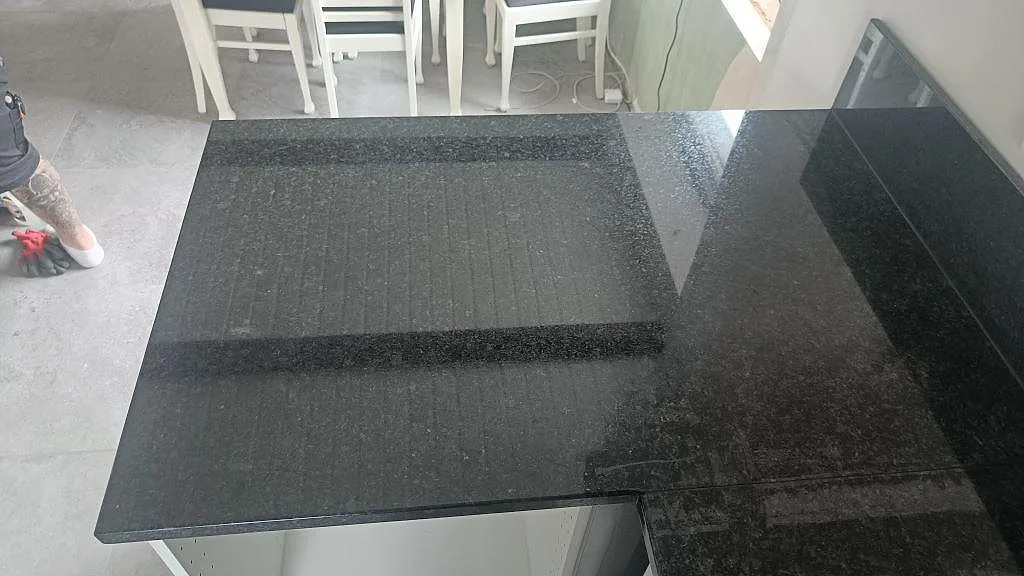 Topptöversikt av polerad svart Angola Black granitbänk i ett kök i Staffanstorp, med synlig ådring och fint kristallspeckle under montering.