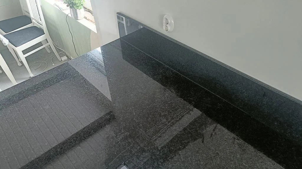 Underlimmad fyrkantig svart kompositdiskho med rostfri silkorg i bänk av svart Angola Black granit i Staffanstorp.