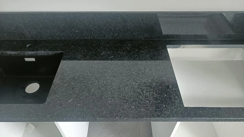 Köksbänk i svart Angola Black granit i Staffanstorp med urtag för häll och underlimmad diskho, sett ovanifrån under montering.