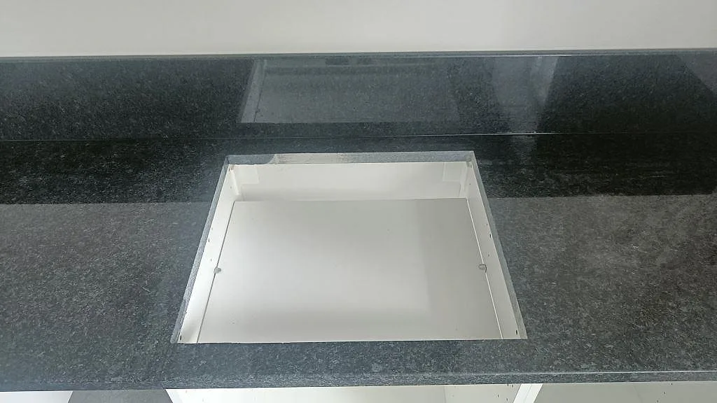 Köksbänk i svart Angola Black granit i Staffanstorp med rektangulärt urtag för inbyggnadsenhet, fotad under montering.