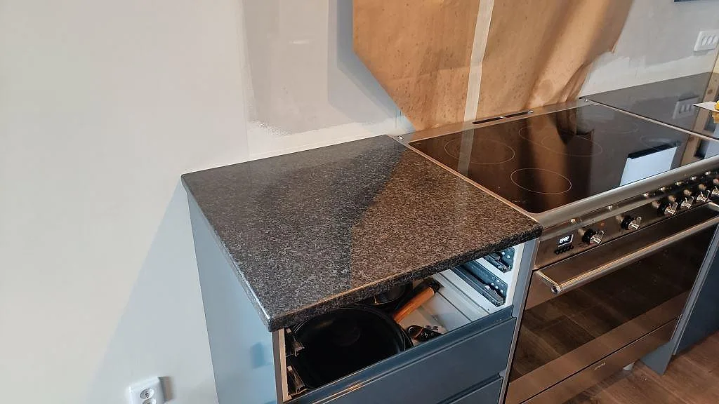 Polerad köksbänkskiva i Angola Black granit vid spishäll, fotad under montering i ett kök i Staffanstorp.