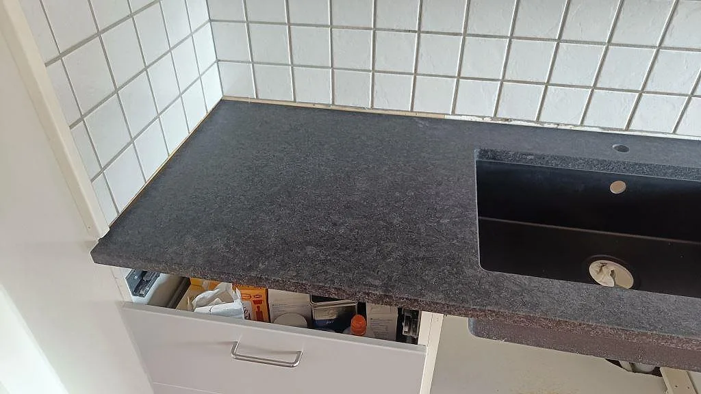 Detalj av matt Angola Black granit med svart diskho och synlig stenyta i ett kök i Staffanstorp.