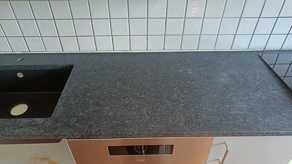 Matt Angola Black granit runt svart diskho och arbetsyta framför vit kakelvägg i ett kök i Staffanstorp.
