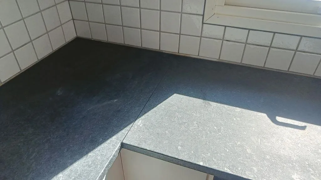 Matt Angola Black granitbänkskiva vid fönsterhörn i ett kök under montering i Staffanstorp.