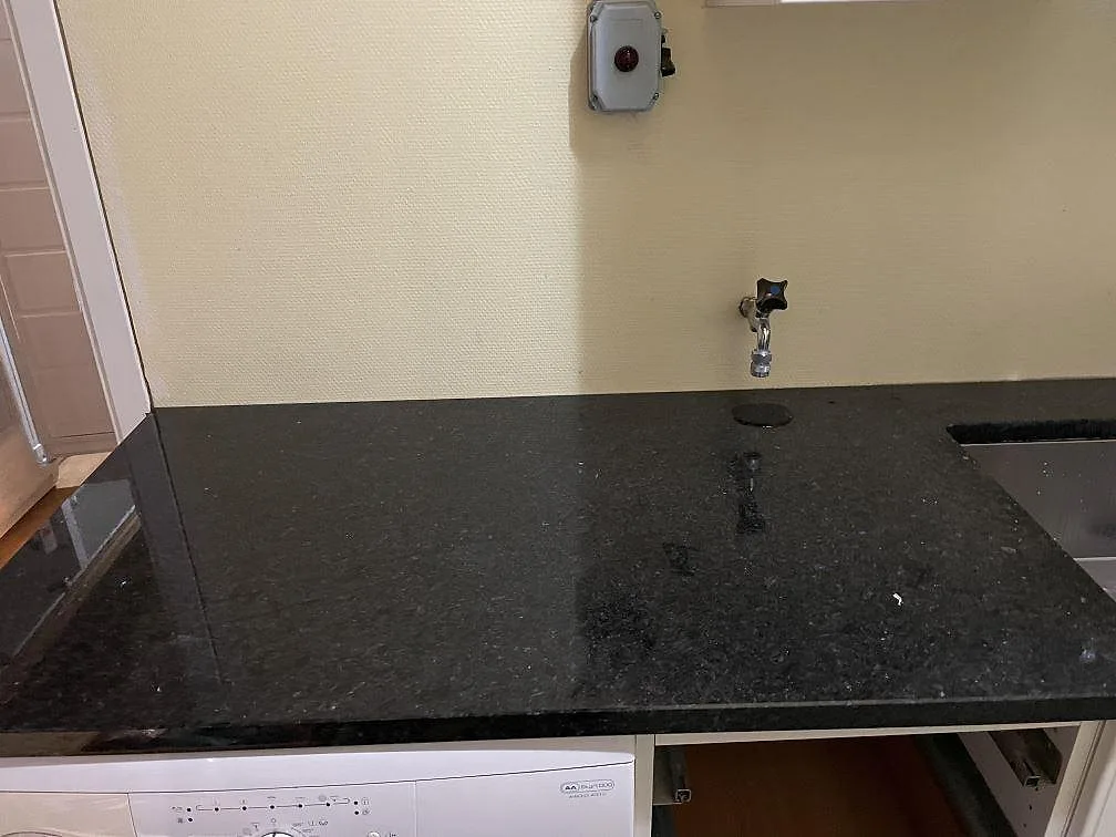 Vänster bänkdel i polerad Angola Black granit med blank yta och del av diskho i Tibro.