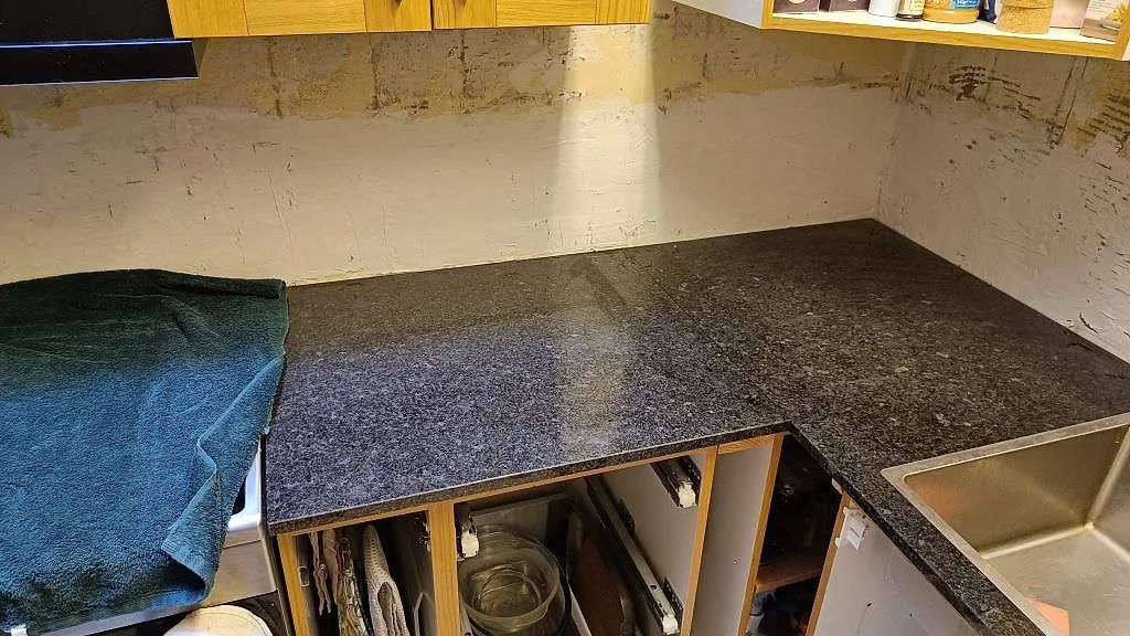 Närbild på hörndel av köksbänkskiva i polerad Angola Black granit med mörk stenstruktur i Tibro.