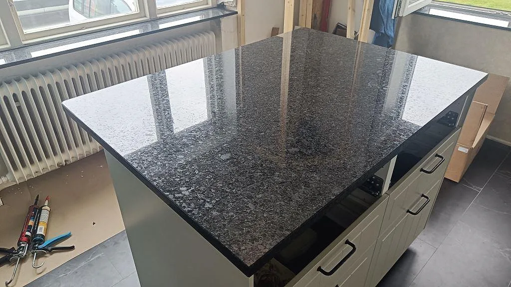 Närbild på stor köksbänkskiva i polerad Angola Black granit vid fönster i Tomelilla.