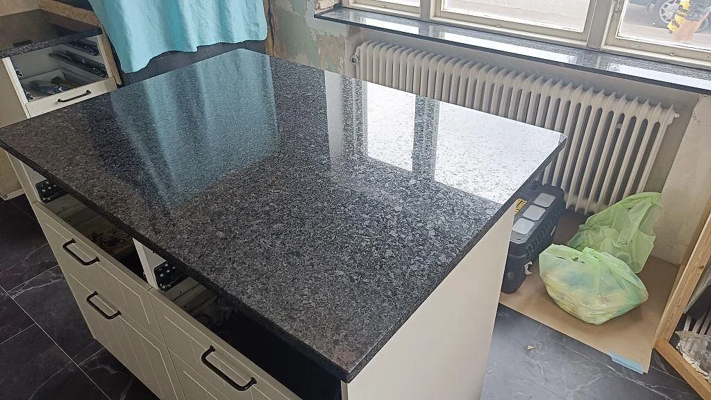Stor arbetsyta i polerad Angola Black granit vid fönster med tydlig naturstensstruktur i Tomelilla.