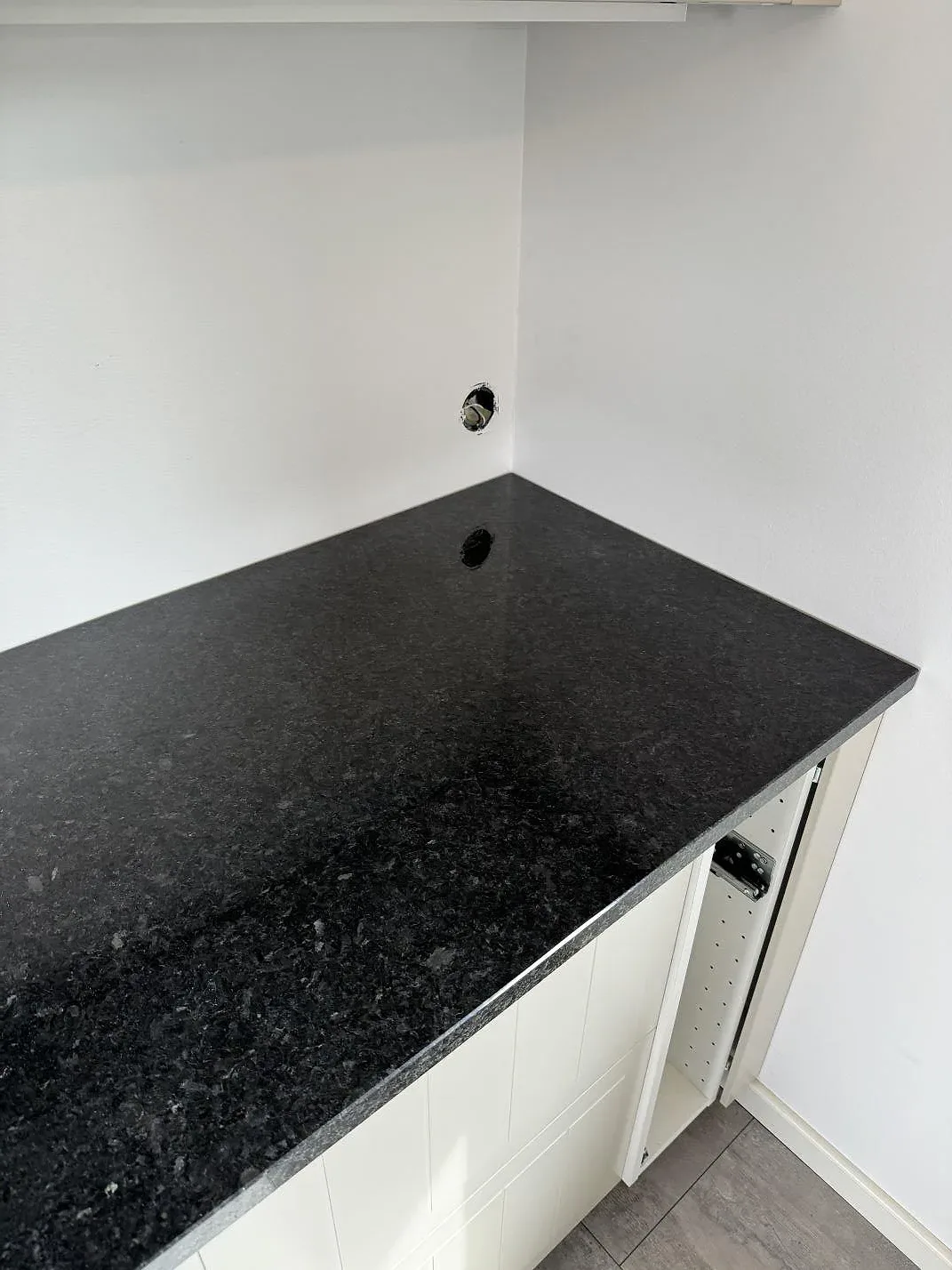 Polerad Angola Black granitbänkskiva med rak kant och mörk stenstruktur vid vita köksstommar i Vellinge.