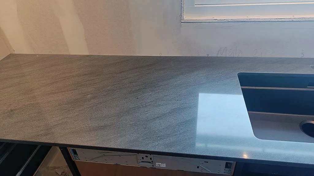 Köksbänkskiva i Anthracite Elegante granit, polerad, med diskhoöppning och fönsterljus i ett kök i Frillesås.