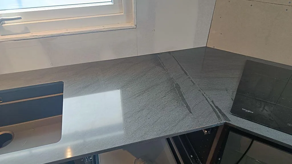 Köksbänkskiva i Anthracite Elegante granit, polerad, med svart underlimmad diskho, häll och hörnskarv i Frillesås.