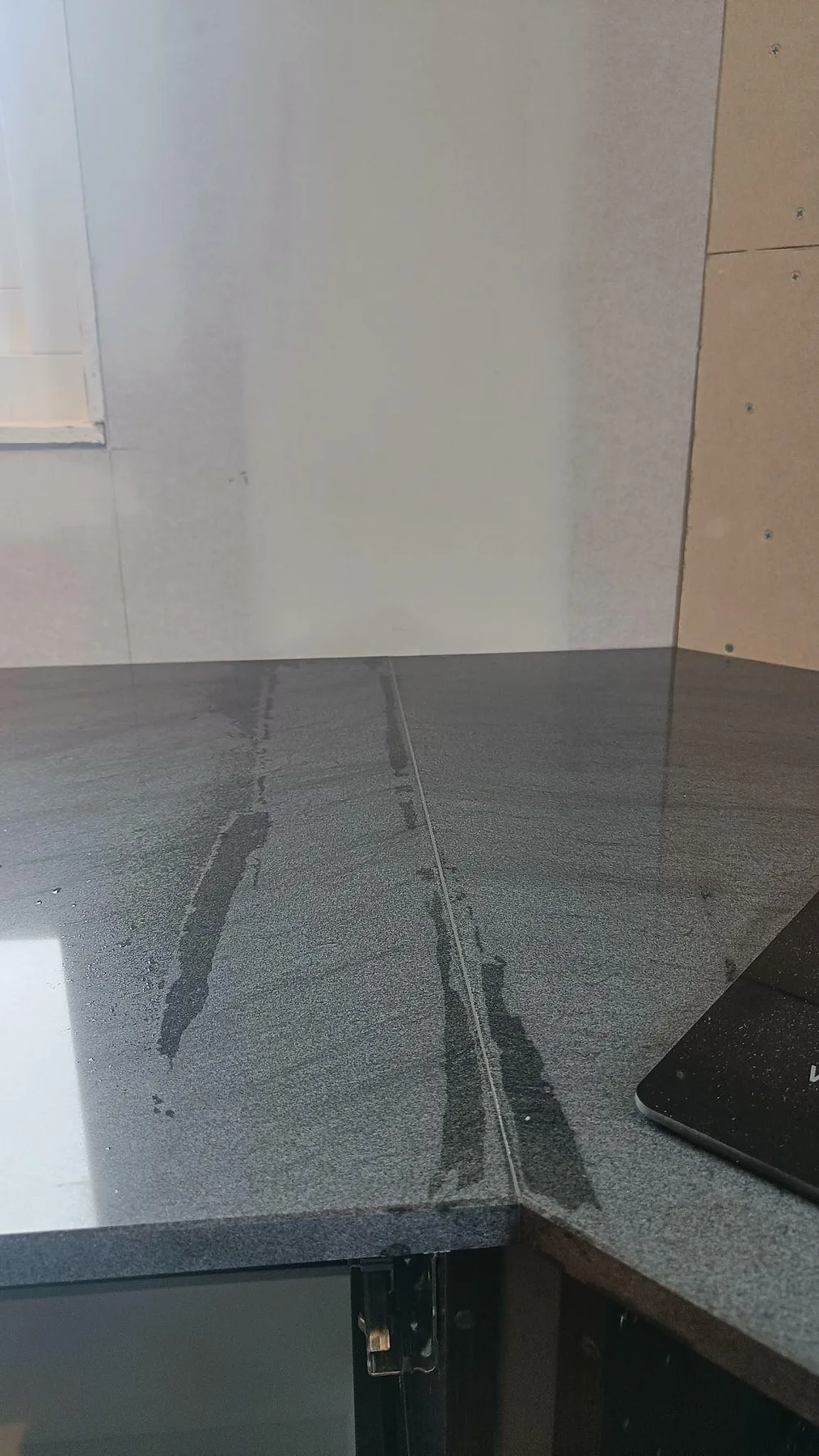 Detalj av polerad Anthracite Elegante granit med hörnskarv och hällkant i ett kök under montering i Frillesås.