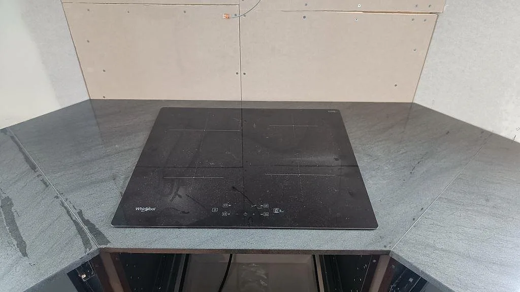 Köksbänkskiva i Anthracite Elegante granit, polerad, med svart induktionshäll och L-formad skarv i ett kök i Frillesås.