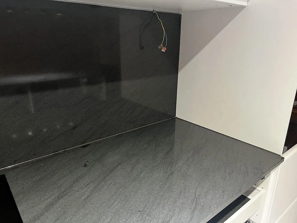 Polerad köksbänkskiva och stänkskydd i Anthracite Elegante granit monterade mot vita skåp i Malmö.