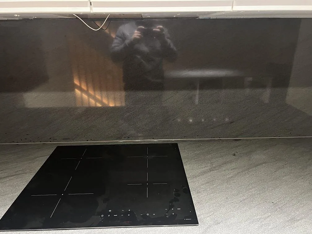 Polerad bänkskiva och mörkt stänkskydd i Anthracite Elegante granit med induktionshäll i Malmö.
