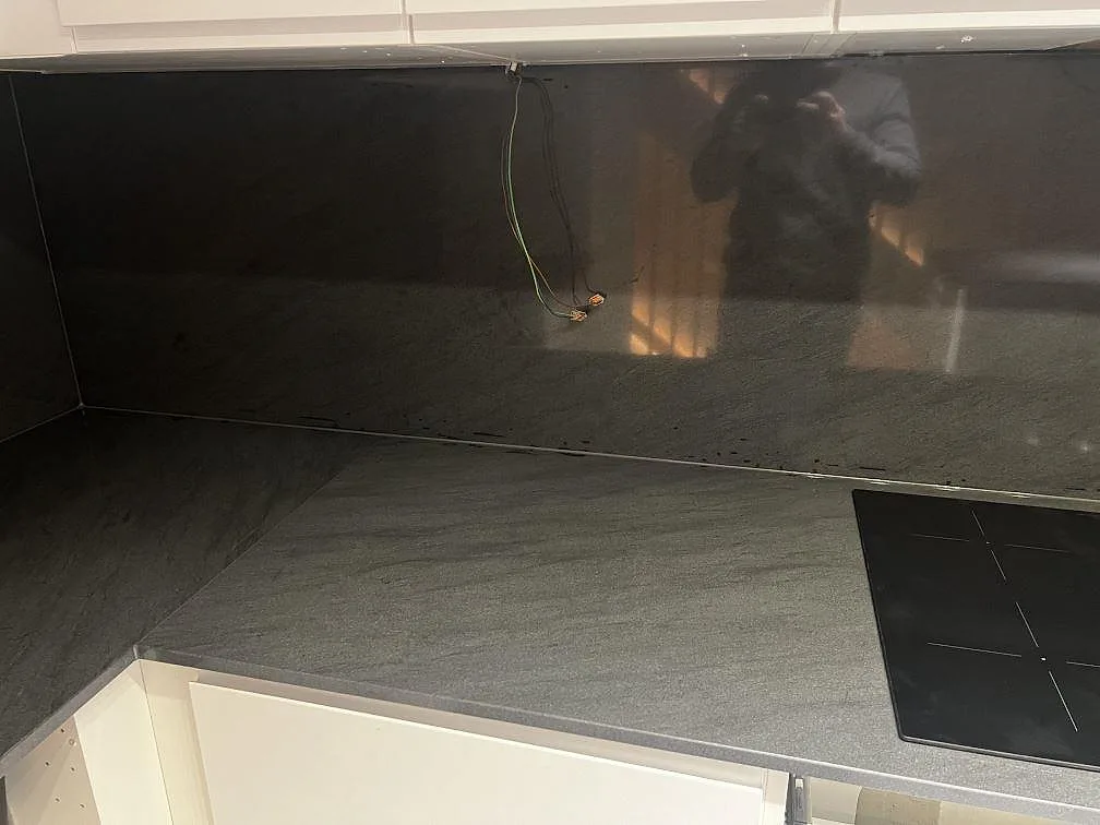 Köksbänkskiva i polerad granit Anthracite Elegante med stänkskydd och svart induktionshäll i ett kök i Malmö.