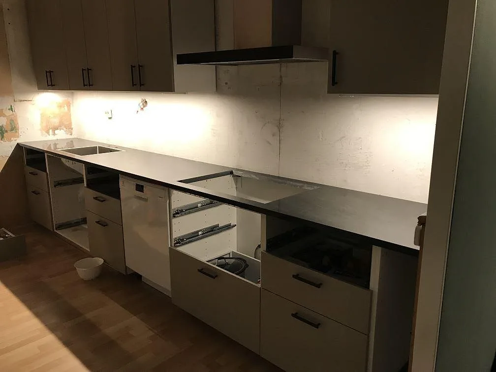 Köksbänkskiva i mörk antracitgrå granit Anthracite Elegante installerad längs en lång rak bänkrad med underlimmad diskho i ett kök i Mölndal.