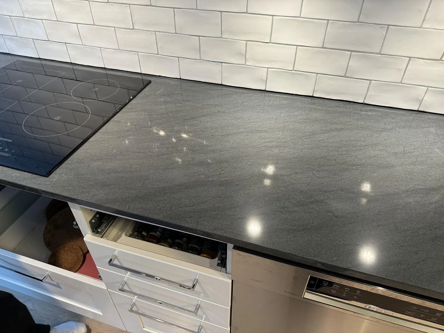 Polerad köksbänkskiva i Anthracite Elegante granit med infälld häll och vit kakelvägg i Partille.