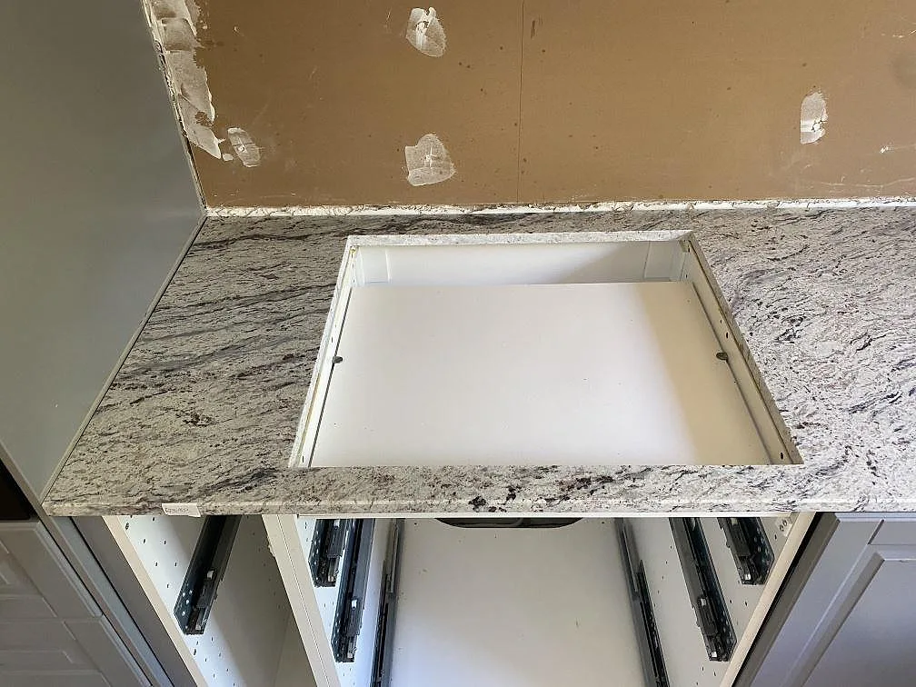 Närbild av polerad Antique White granit runt en diskhoöppning, monterad på öppna köksstommar i Älmhult.