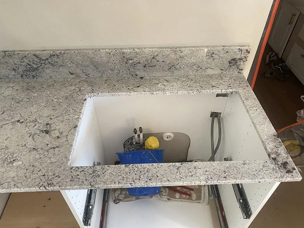 Underlimmad diskho i urtaget i en köksbänkskiva av Antique White-granit, sedd ovanifrån i ett kök i Borrby.