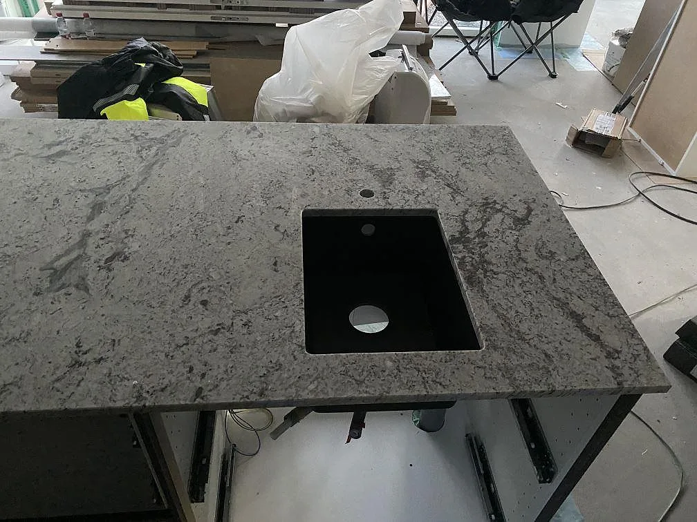 Detalj av svart diskho i köksbänkskiva av polerad Antique White granit i Falkenberg.