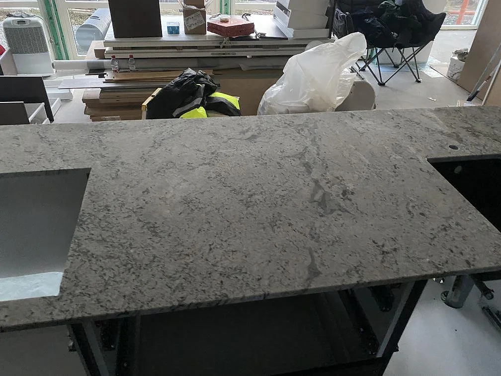 Polerad köksbänkskiva i Antique White granit längs fönstervägg med spegling i stenen i ett kök i Falkenberg.