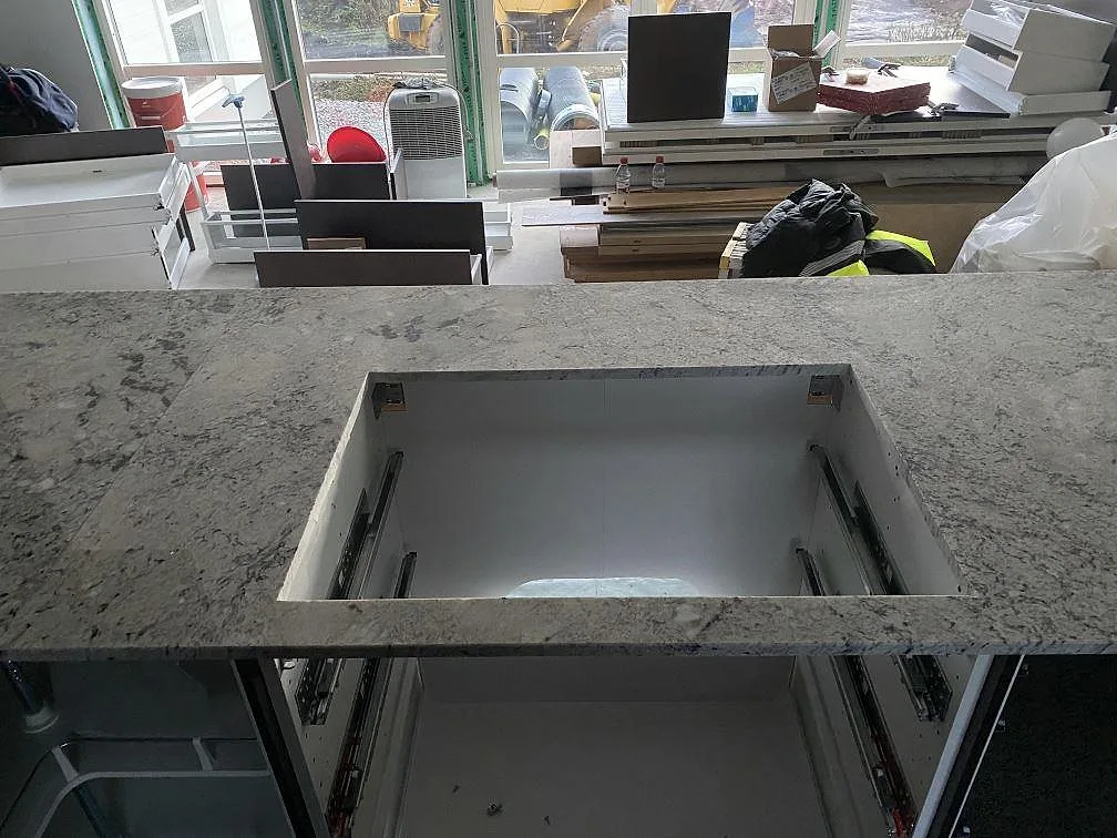 Köksbänkskiva i Antique White granit med urtag monterad på köksstommar, polerad yta, i ett kök i Falkenberg.