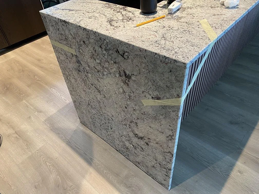Köksö i Antique White granit med polerad kant och varm krämvit ådring i ett kök i Falkenberg.
