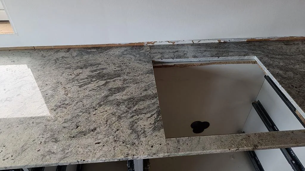 Bänkskiva i Antique White-granit med urtag för häll, polerad yta och naturlig ådring i ett kök i Frillesås.