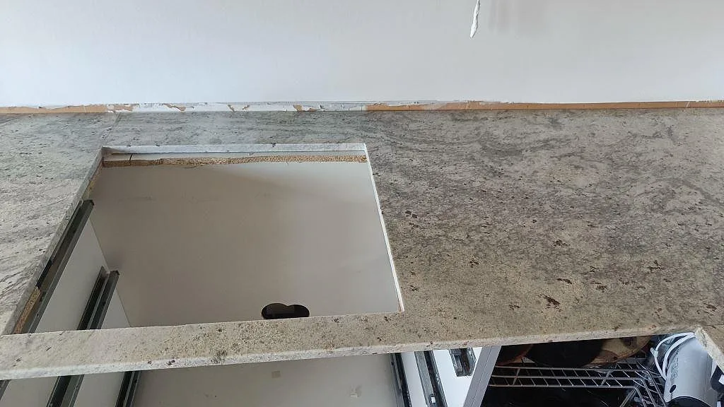Ovanifrån på köksbänk i Antique White-granit med urtag för häll och polerad yta, Frillesås.